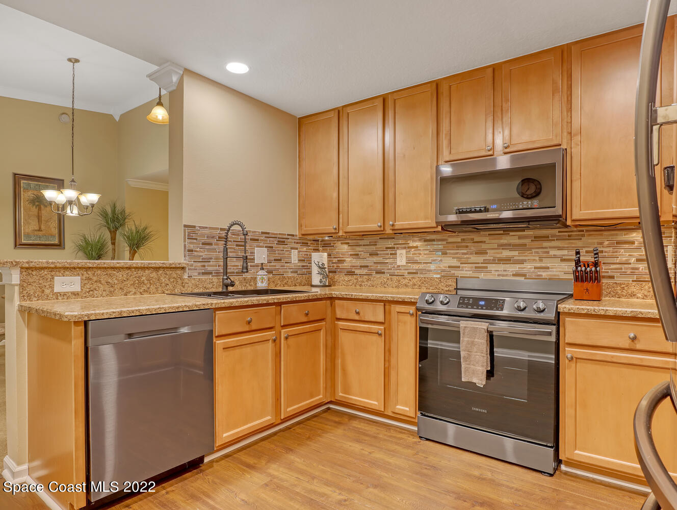 4077 Meander Place Rockledge, FL 32955 - Photo 5 of 24 a kitchen with stainless steel appliances granite countertop wooden cabinets a sink a stove a refrigerator and island with wooden floor