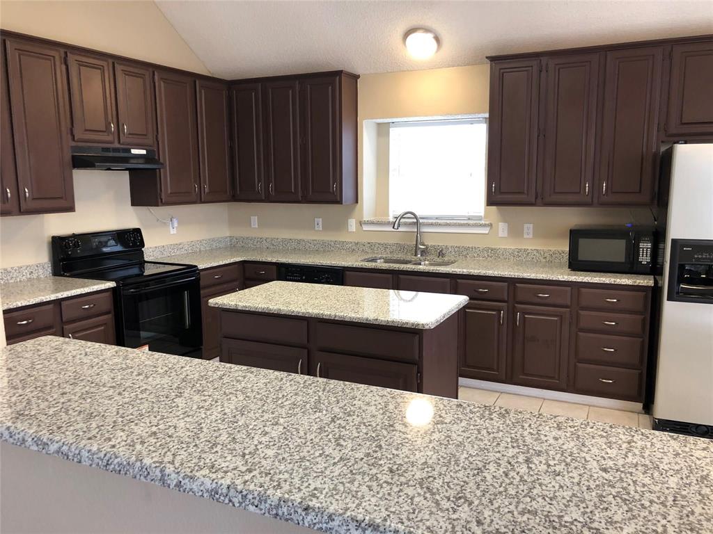 8301 Bells Street Frisco, TX 75035 - Photo 9 of 24 a kitchen with wooden cabinets a sink and a stove