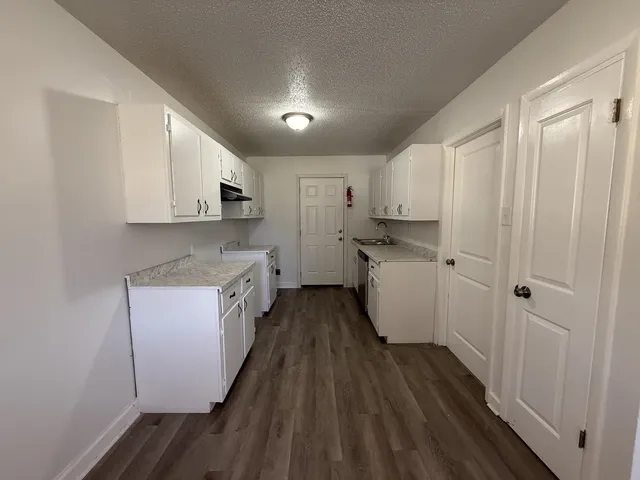 a kitchen with white cabinets and a stove with wooden floor