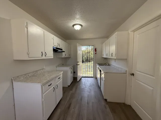 a view of a kitchen with granite countertop cabinets appliances and a wooden floor
