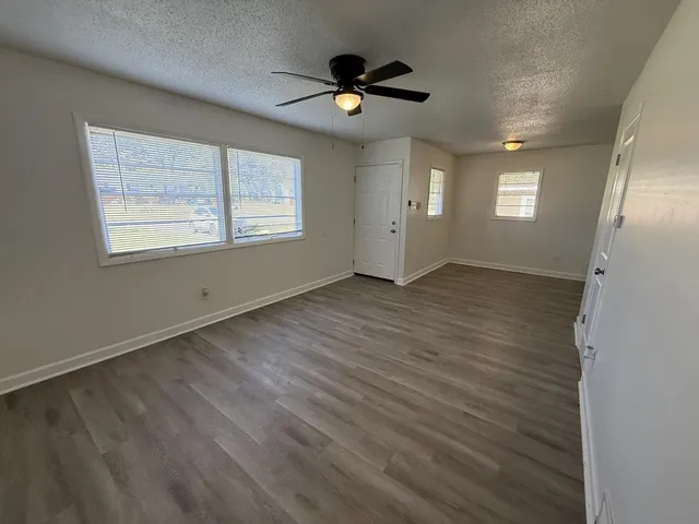 an empty room with wooden floor and windows