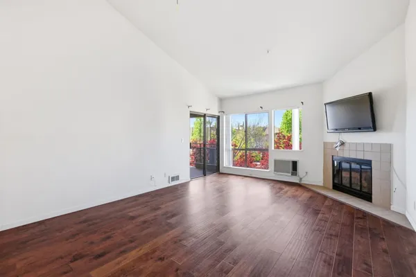 a view of a livingroom with a fireplace a ceiling fan and wooden floor