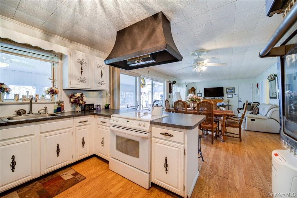 307 Beaver Lake Road Livingston Manor, NY 12758 - Photo 21 of 36 a open kitchen with stainless steel appliances granite countertop a stove a sink dishwasher and white cabinets with wooden floor