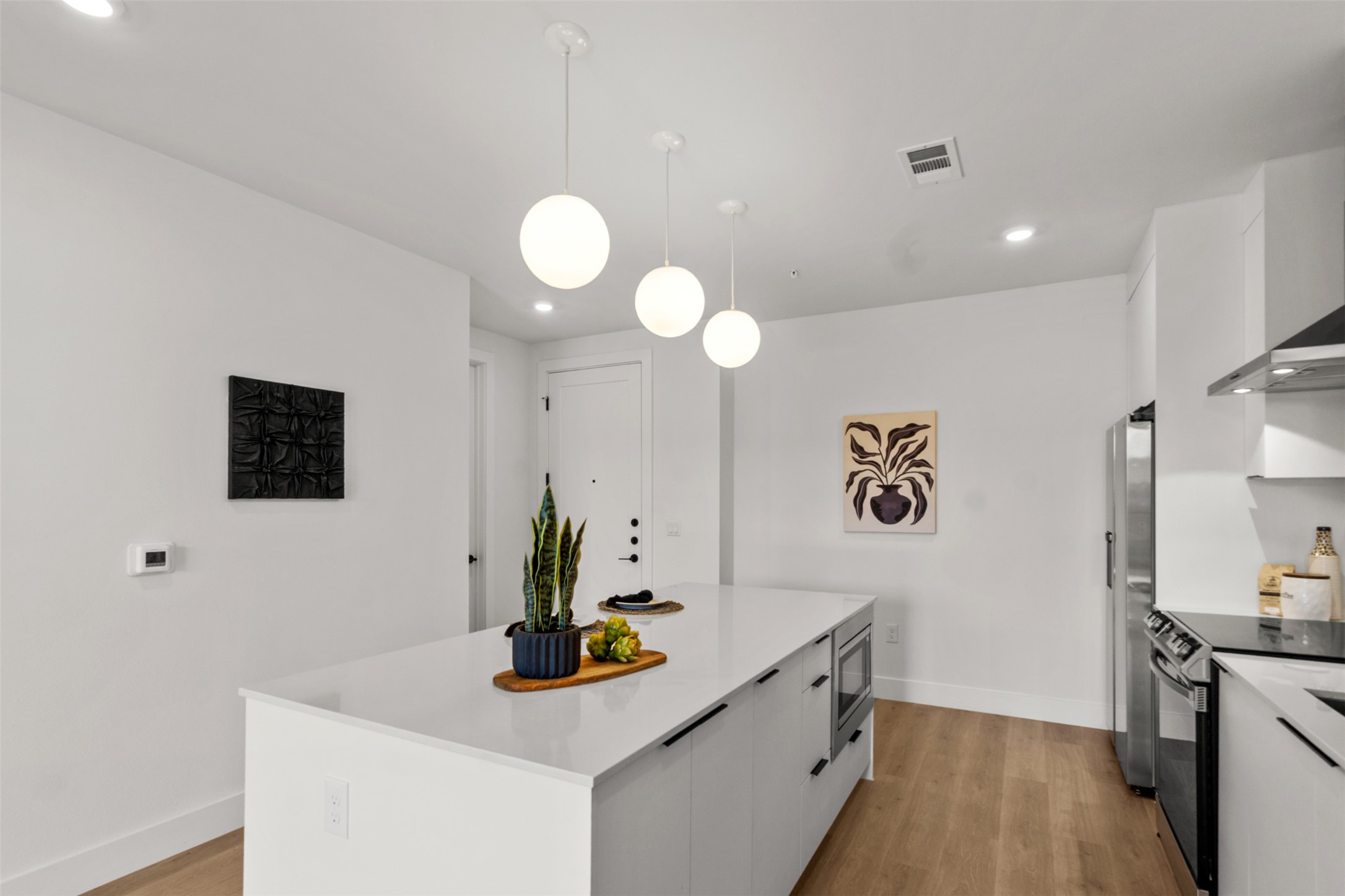 1701 Simond Avenue, Unit 418 Austin, TX 78723 - Photo 7 of 37 Kitchen featuring white cabinets, a center island, modern cabinets, and stainless steel appliances.
