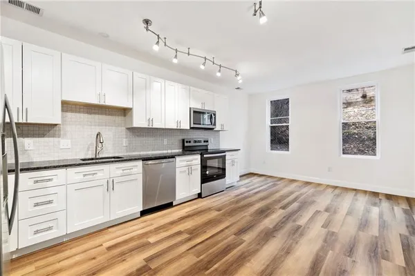 a kitchen with granite countertop a stove a sink and a refrigerator