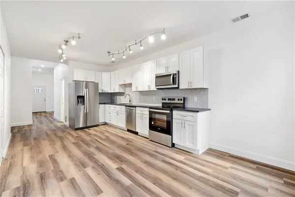 a kitchen with granite countertop a refrigerator stove top oven and sink
