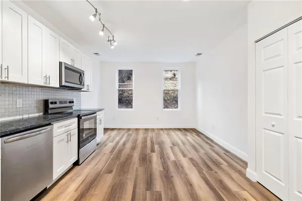 a kitchen with granite countertop stainless steel appliances sink cabinets and window
