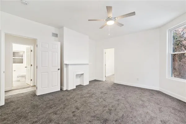 an empty room with windows and fan
