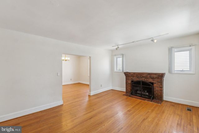 an empty room with wooden floor fireplace and a window