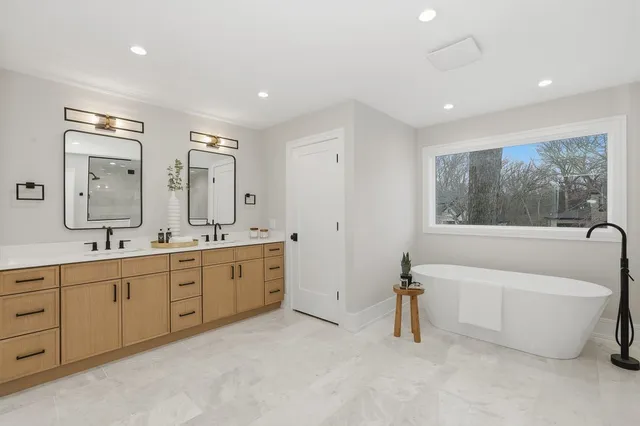 a bathroom with double vanity sink a two mirror a window a bathtub and shower