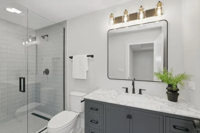 a bathroom with a granite countertop sink a toilet and shower