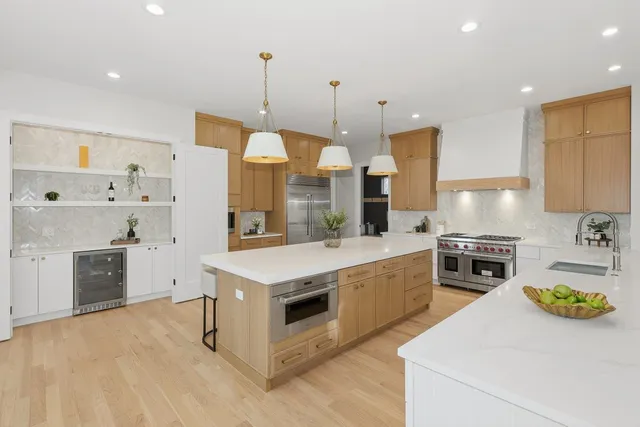 a kitchen with a stove a refrigerator a sink a oven and chairs