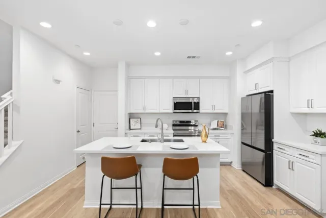 a kitchen with a sink a microwave a refrigerator and white cabinets
