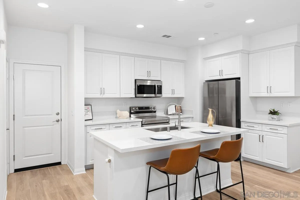 10149 Graphite Street Spring Valley, CA 91977 - Photo 10 of 35 a kitchen with a sink a microwave a refrigerator and white cabinets