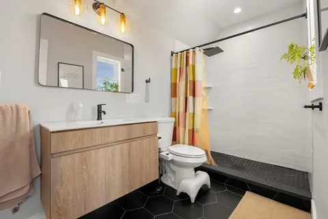 a bathroom with a sink toilet a mirror and shower