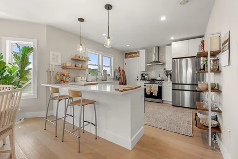 a kitchen with stainless steel appliances a refrigerator a stove a sink a dining table and chairs