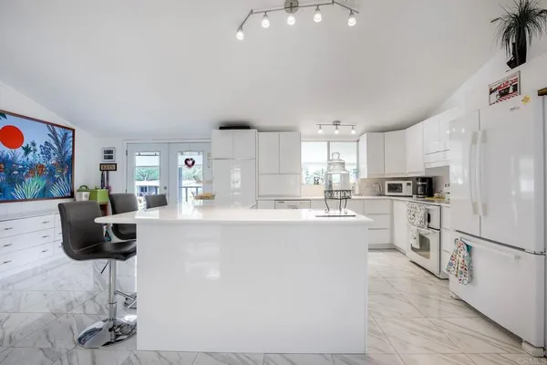 a kitchen with stainless steel appliances granite countertop a refrigerator a stove a sink a dining table and chairs with wooden floor