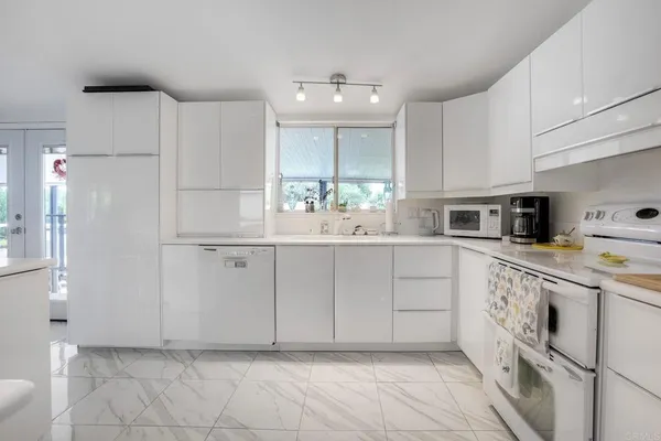 a kitchen with white cabinets and white appliances