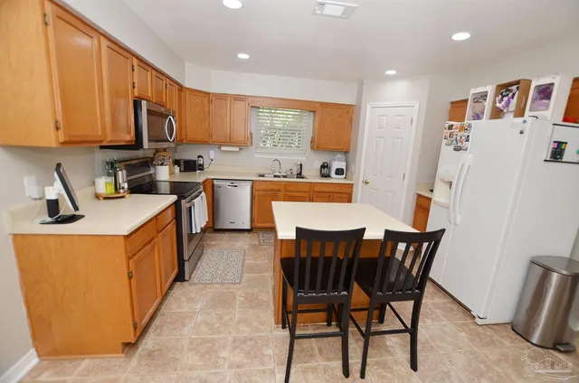 a kitchen with stainless steel appliances granite countertop a table chairs sink refrigerator and cabinets
