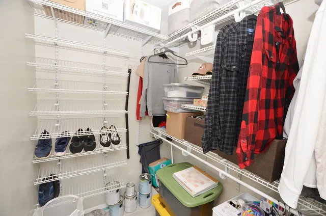 a view of walk in closet with clothes and shoes