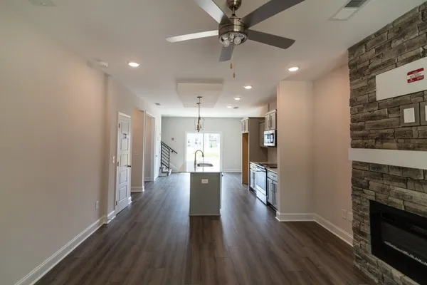 a view of a hallway with wooden floor and a kitchen