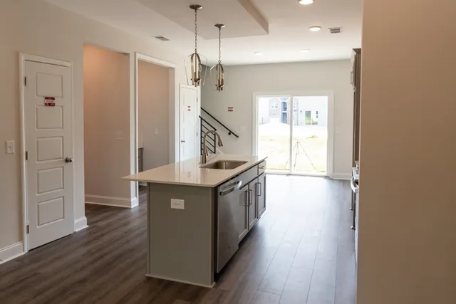 a kitchen with stainless steel appliances granite countertop a sink a stove and a wooden floor