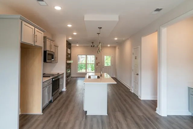 a large kitchen with a center island wooden floor stainless steel appliances and cabinets