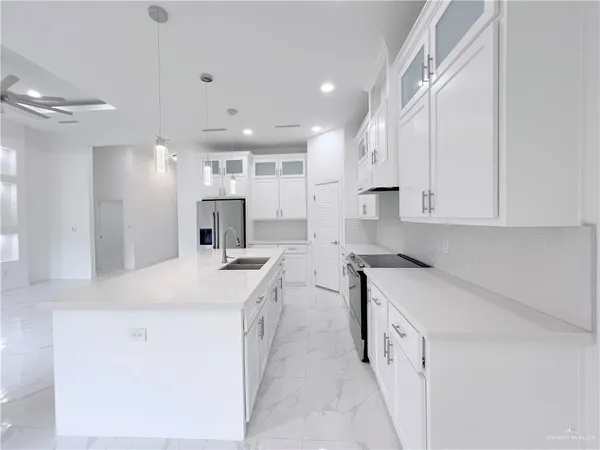 a kitchen that has a lot of white cabinets and stainless steel appliances
