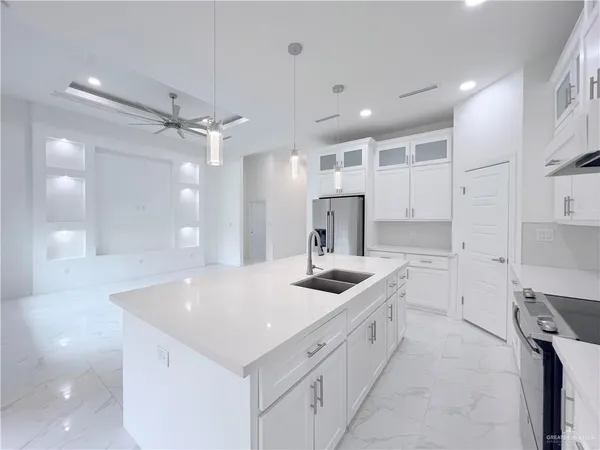 a kitchen with stainless steel appliances a sink a stove a refrigerator and cabinets