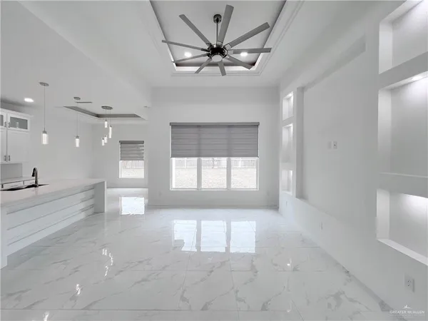 a view of an empty room and window a ceiling fan and wooden floor