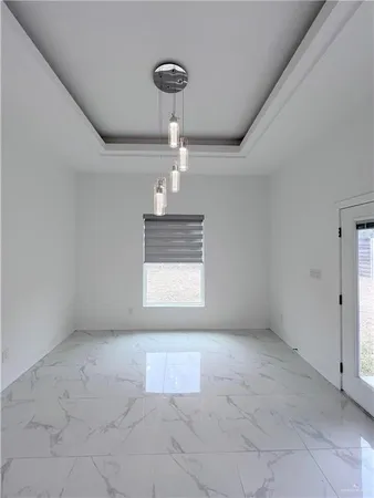 a view of an empty room and chandelier fan