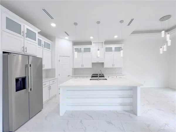 a large white kitchen with a refrigerator a stove and a sink