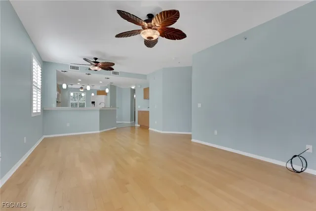 wooden floor in an empty room with a chandelier fan