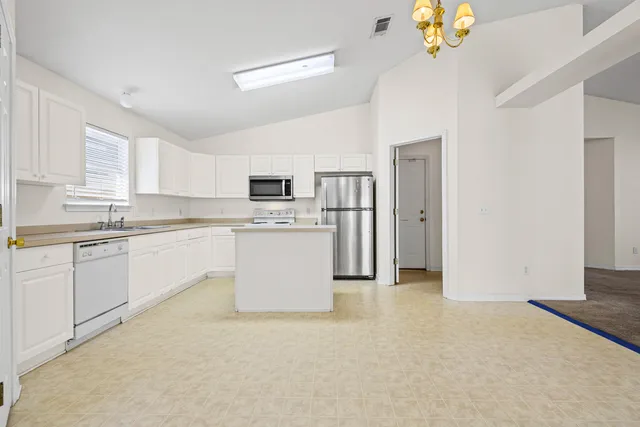 a kitchen with a refrigerator sink and white cabinets