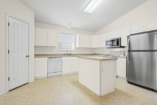 a kitchen with white cabinets and white stainless steel appliances and refrigerator