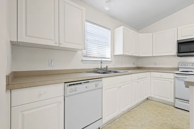 a kitchen with granite countertop white cabinets and white appliances