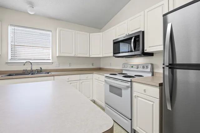 a kitchen with stainless steel appliances granite countertop a refrigerator stove a sink and a microwave