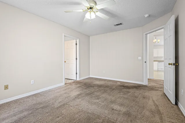 a view of an empty room and chandelier fan