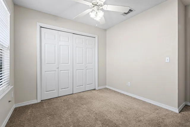 an empty room with fan and windows