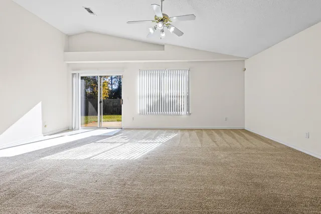 an empty room with windows and ceiling fan