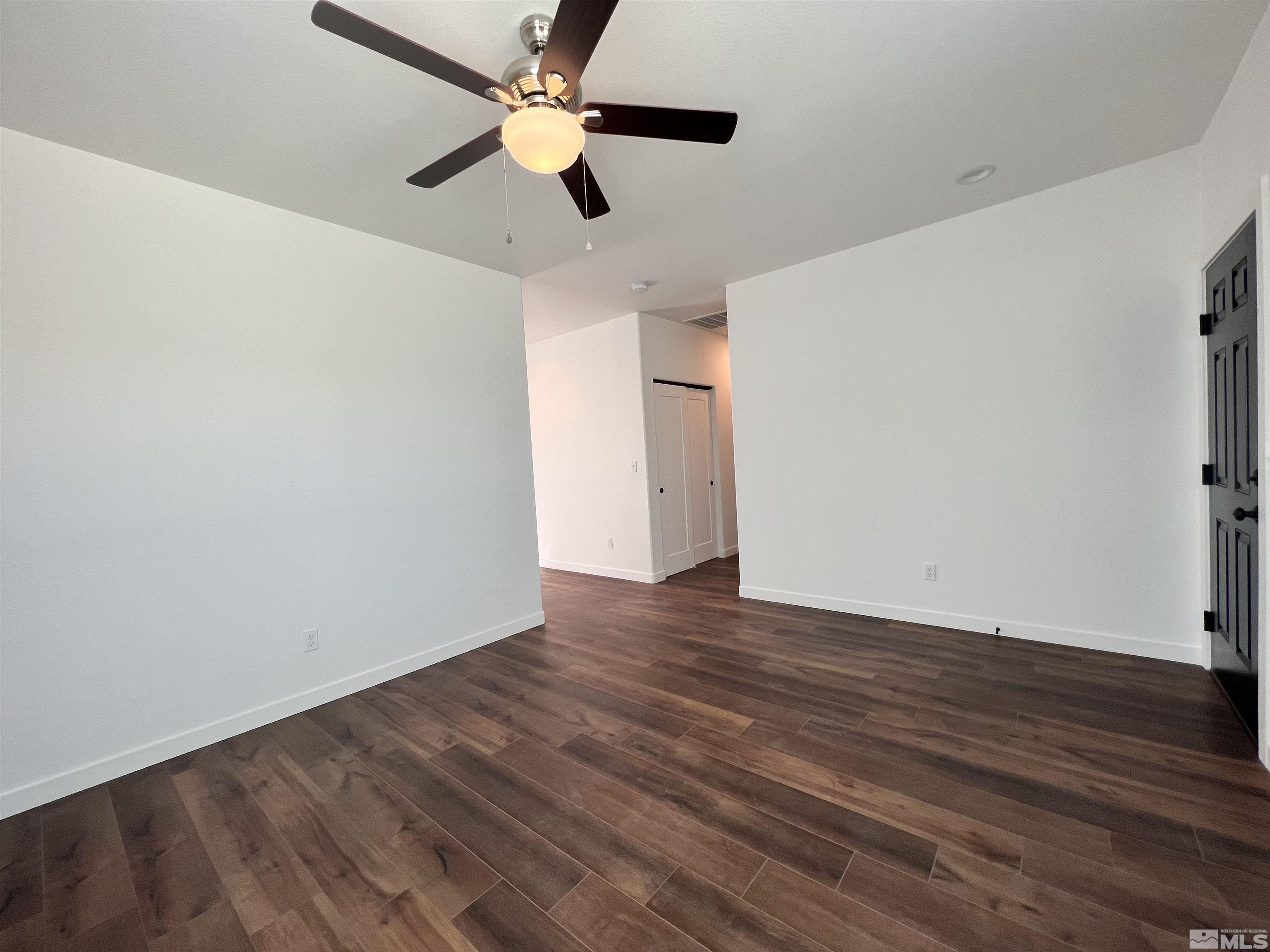 682 Silver Spur Drive Fallon, NV 89406 - Photo 7 of 29 an empty room with wooden floor ceiling fan and ceiling fan