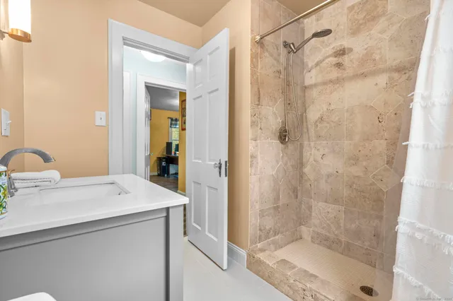 a bathroom with a granite countertop sink two mirror and shower