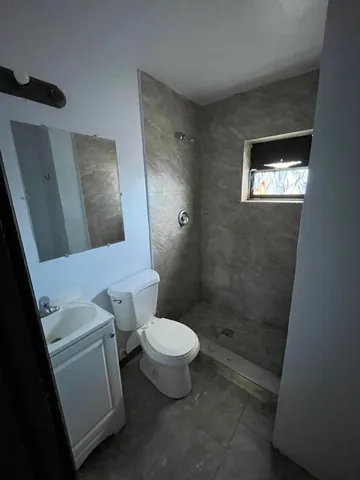 a white toilet sitting next to a bathroom sink and a mirror