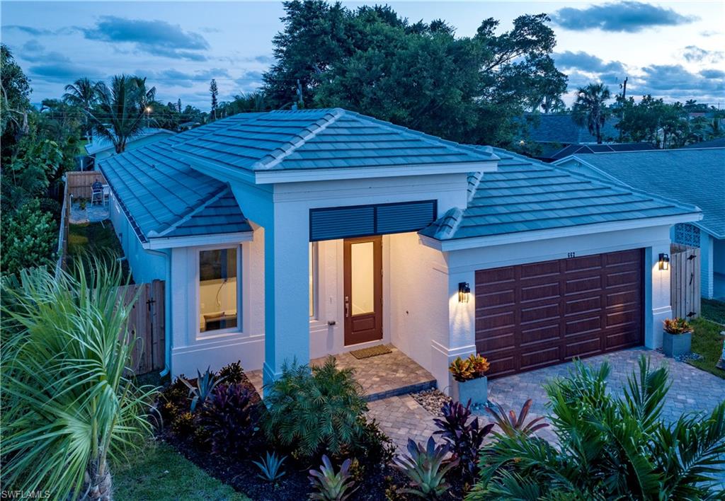 View of front of home featuring a tile roof, fence, an attached garage, stucco siding, and decorative driveway