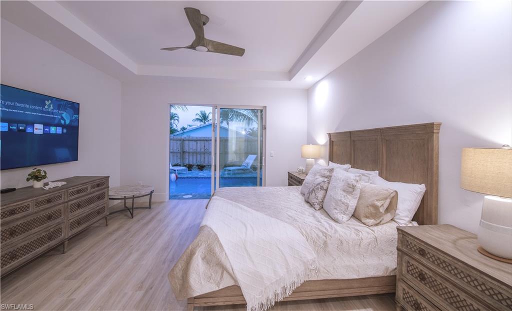 662 105th Avenue North Naples, FL 34108 - Photo 15 of 35 Bedroom with a raised ceiling, ceiling fan, light wood finished floors, and access to outside