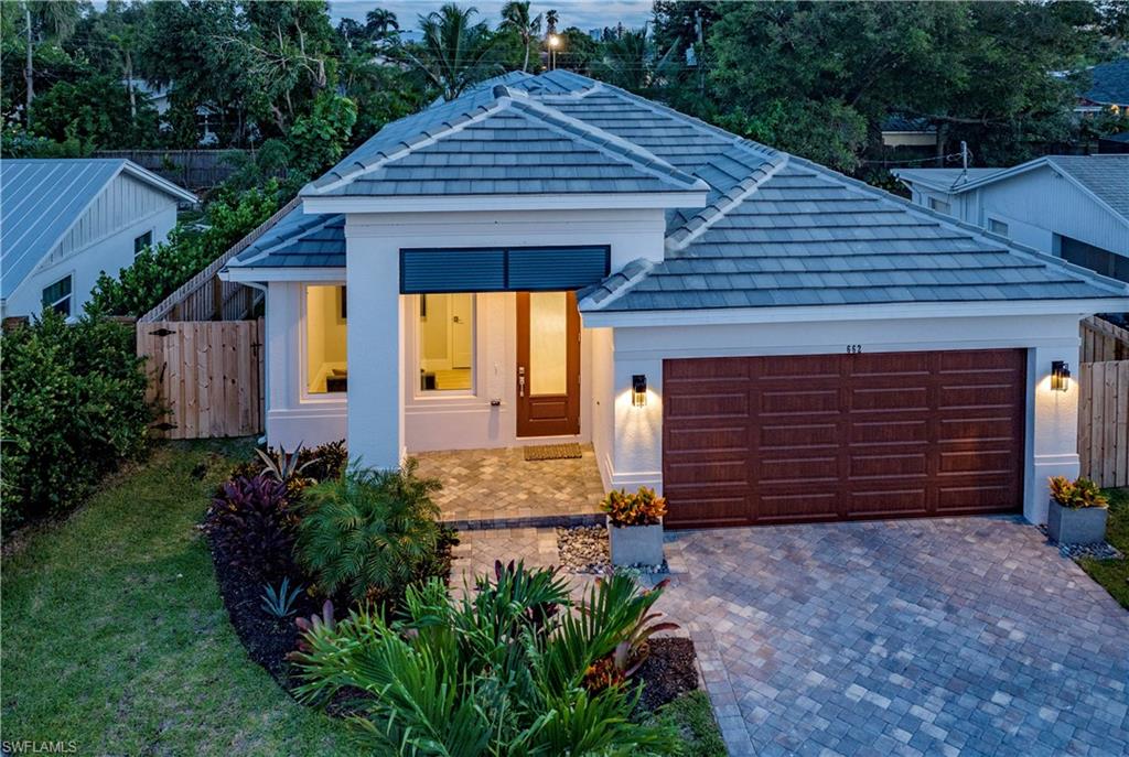 662 105th Avenue North Naples, FL 34108 - Photo 2 of 35 View of front of house with fence, a tile roof, driveway, and a garage
