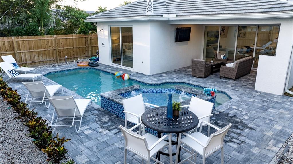 662 105th Avenue North Naples, FL 34108 - Photo 24 of 35 View of swimming pool featuring fence, a patio area, outdoor dining area, and a pool with connected hot tub