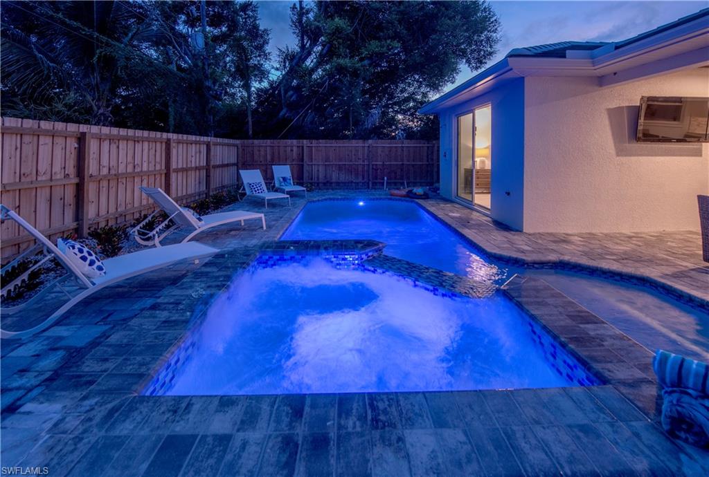 662 105th Avenue North Naples, FL 34108 - Photo 31 of 35 Pool at dusk featuring a fenced backyard, a patio, and a pool with connected hot tub