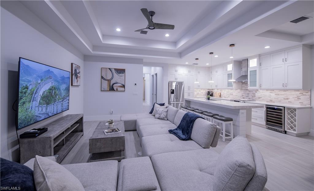 662 105th Avenue North Naples, FL 34108 - Photo 7 of 35 Living area with wine cooler, a tray ceiling, light wood-style flooring, visible vents, and a ceiling fan