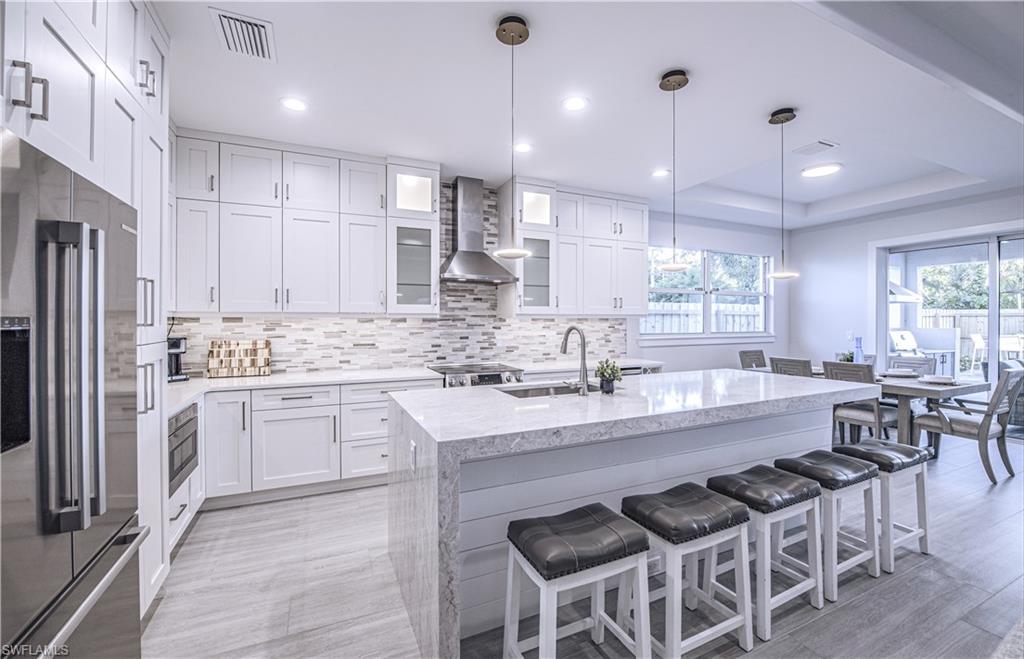 662 105th Avenue North Naples, FL 34108 - Photo 9 of 35 Kitchen featuring a sink, high quality fridge, backsplash, wall chimney exhaust hood, and visible vents